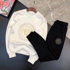 White sweatshirt and black jogger set with gold Medusa emblem and small round logo patch