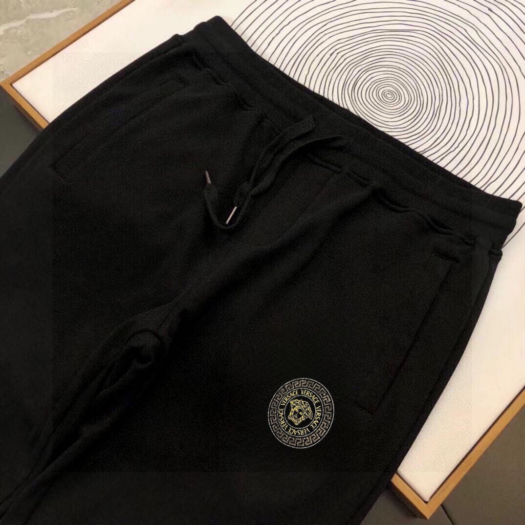 Black jogger pants with drawstring waist and round logo patch on the leg