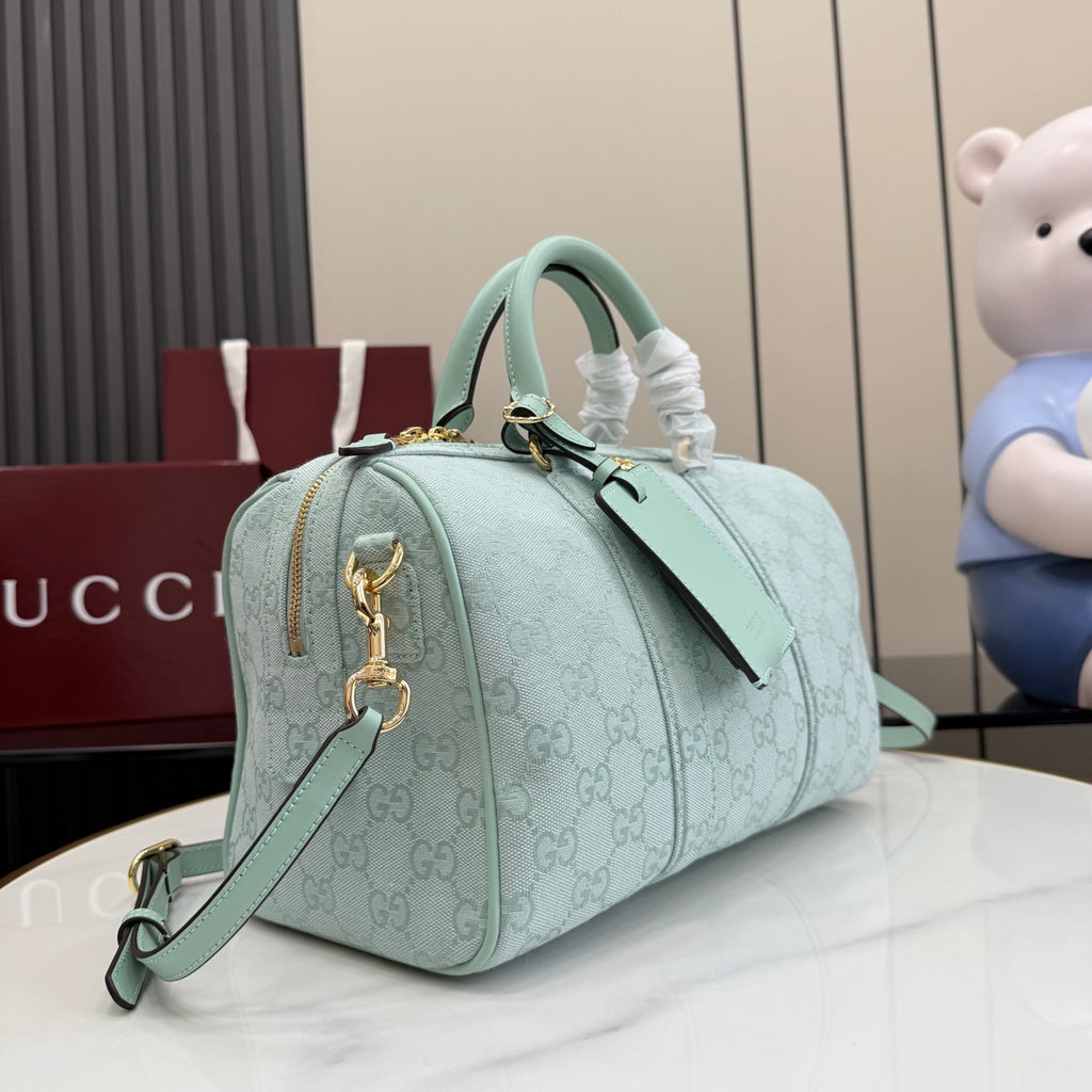 Mint GG-pattern duffle handbag with top handle, chain key fob, and long shoulder strap.