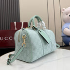 Mint GG-pattern duffle handbag with top handle, chain key fob, and long shoulder strap.