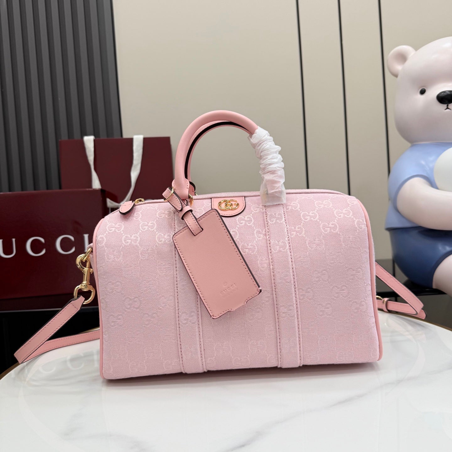 Gucci bag in pale pink with G monogram pattern, top handle and front luggage tag
