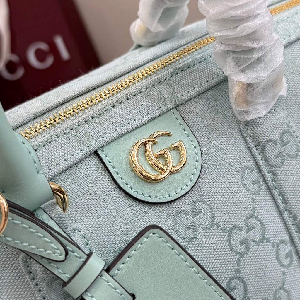Mint leather tab detail on GG-pattern handbag with gold-tone clasp and zip pocket edge.