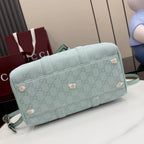 Mint GG-pattern barrel bag with front stud accents and crossbody strap.