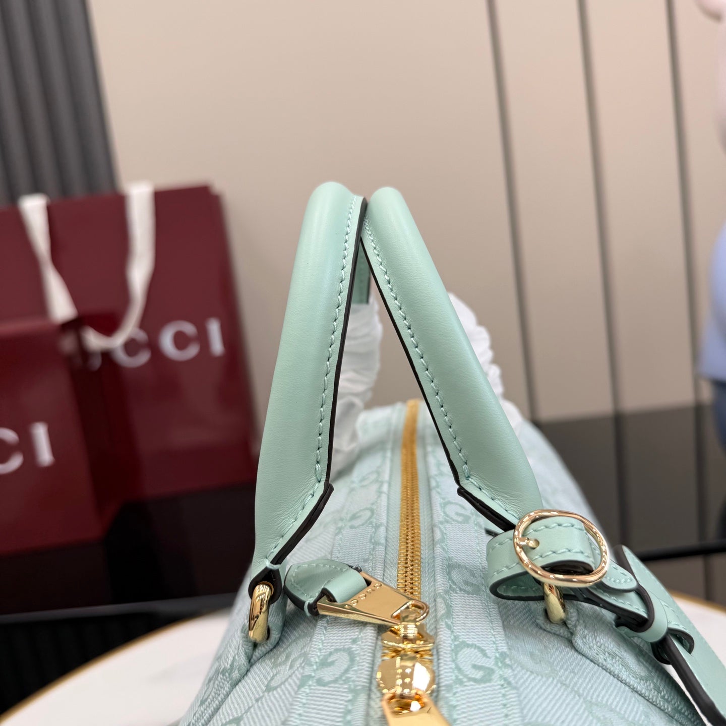 Mint handbag top handle detail with gold-tone hardware and GG-pattern body.