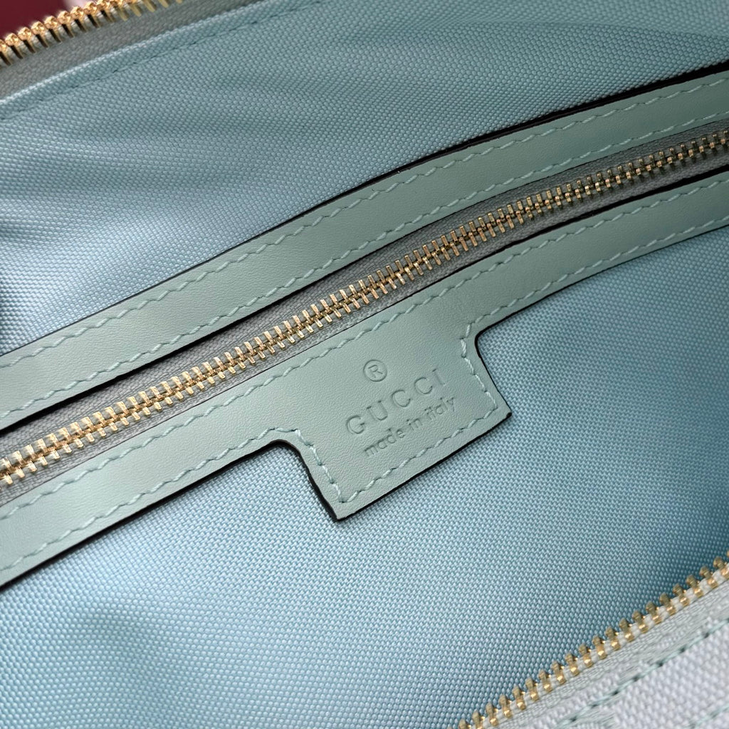 Mint GG-pattern handbag with leather logo patch and gold zipper track on front panel.