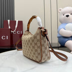 Gucci hobo bag angled view with bamboo handle, leather strap, and GG canvas