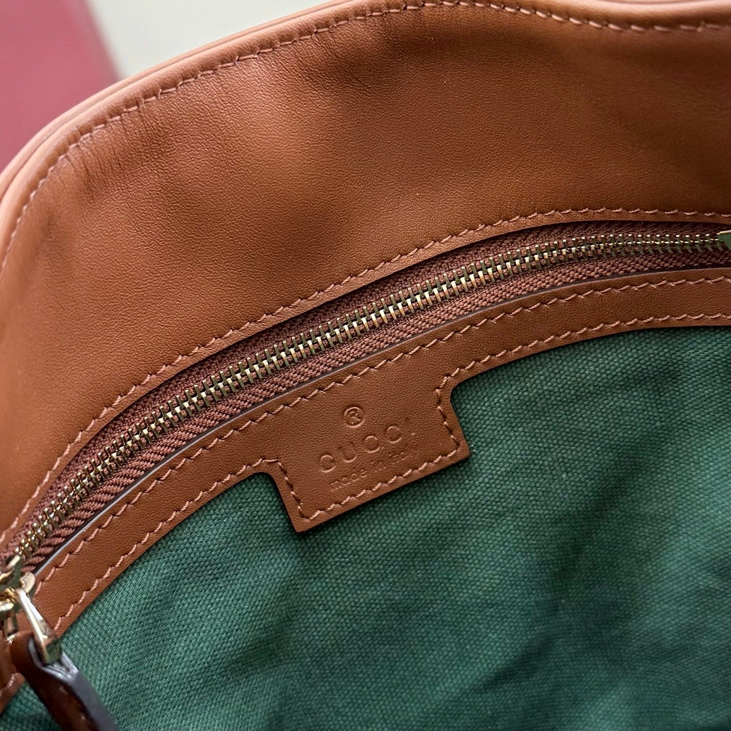Gucci bag interior pocket with leather label, zipper, and green fabric lining