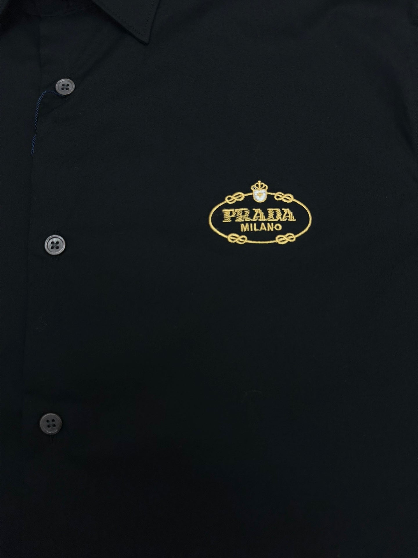 Black long-sleeve shirt with gold Prada crest logo on the chest