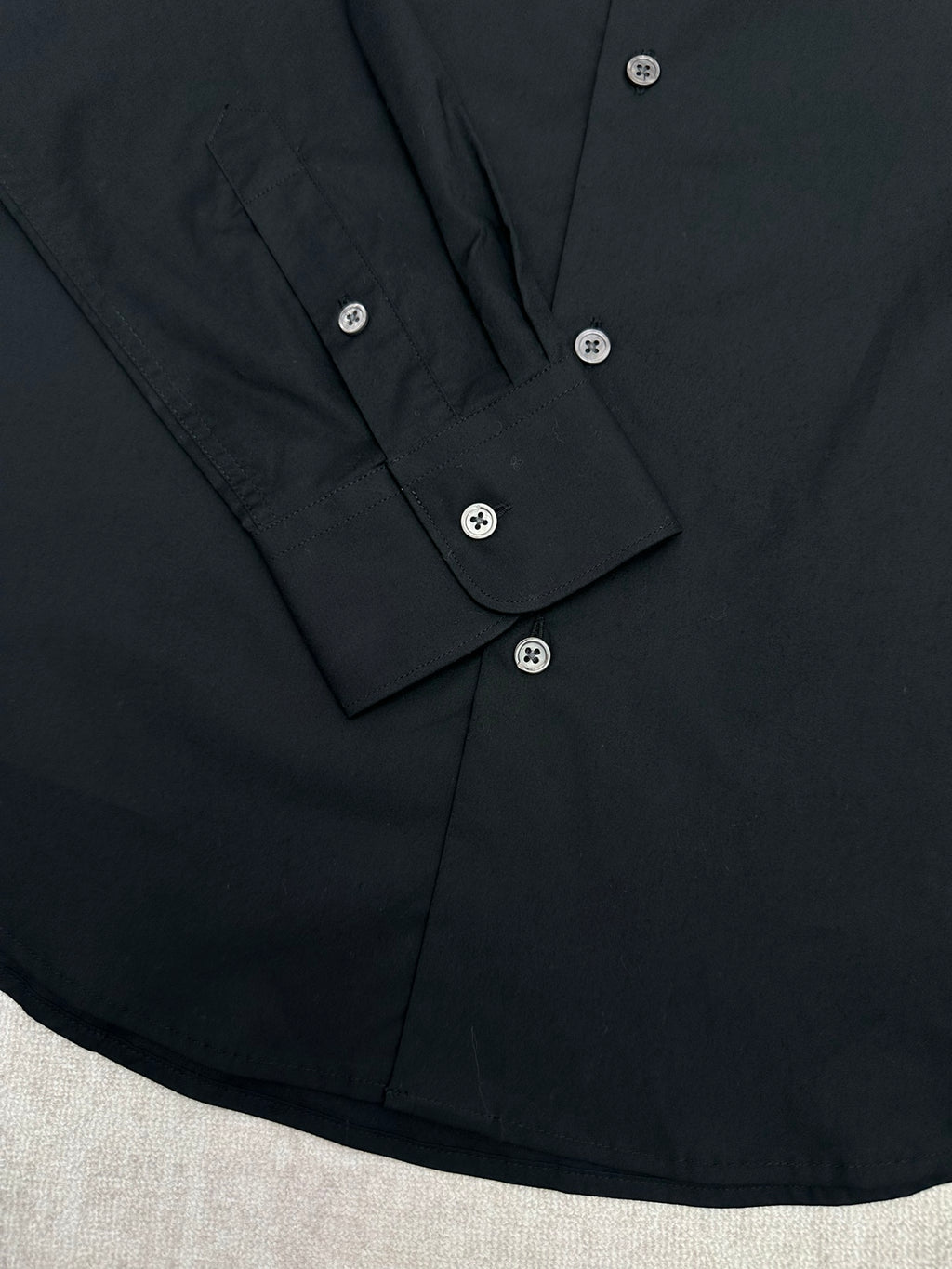 Black long-sleeve shirt button placket with folded cuffs and white buttons