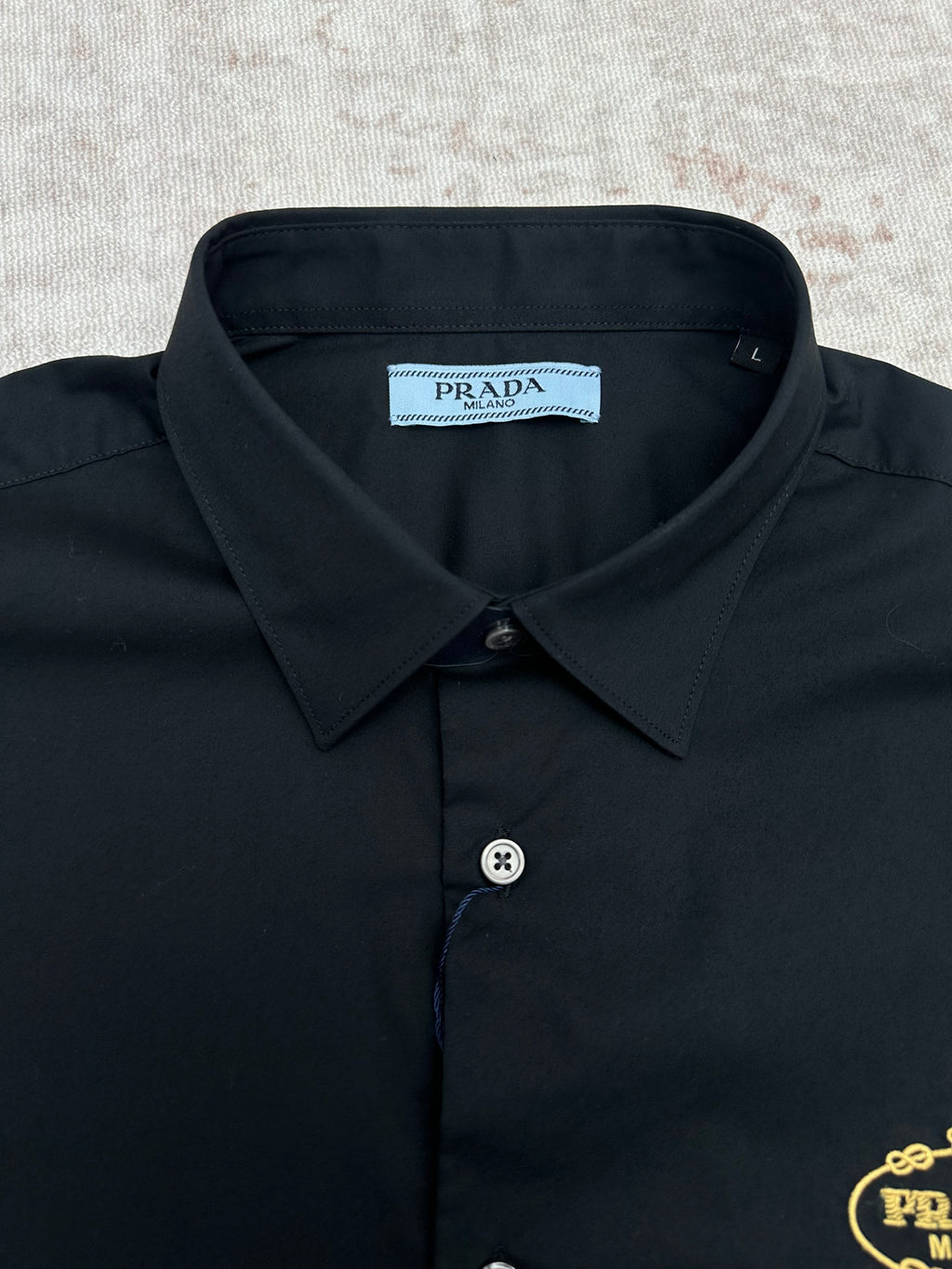Black long-sleeve shirt collar with Prada neck label and button placket