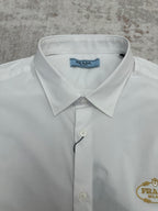 White dress shirt collar close-up with gold Prada crest and button