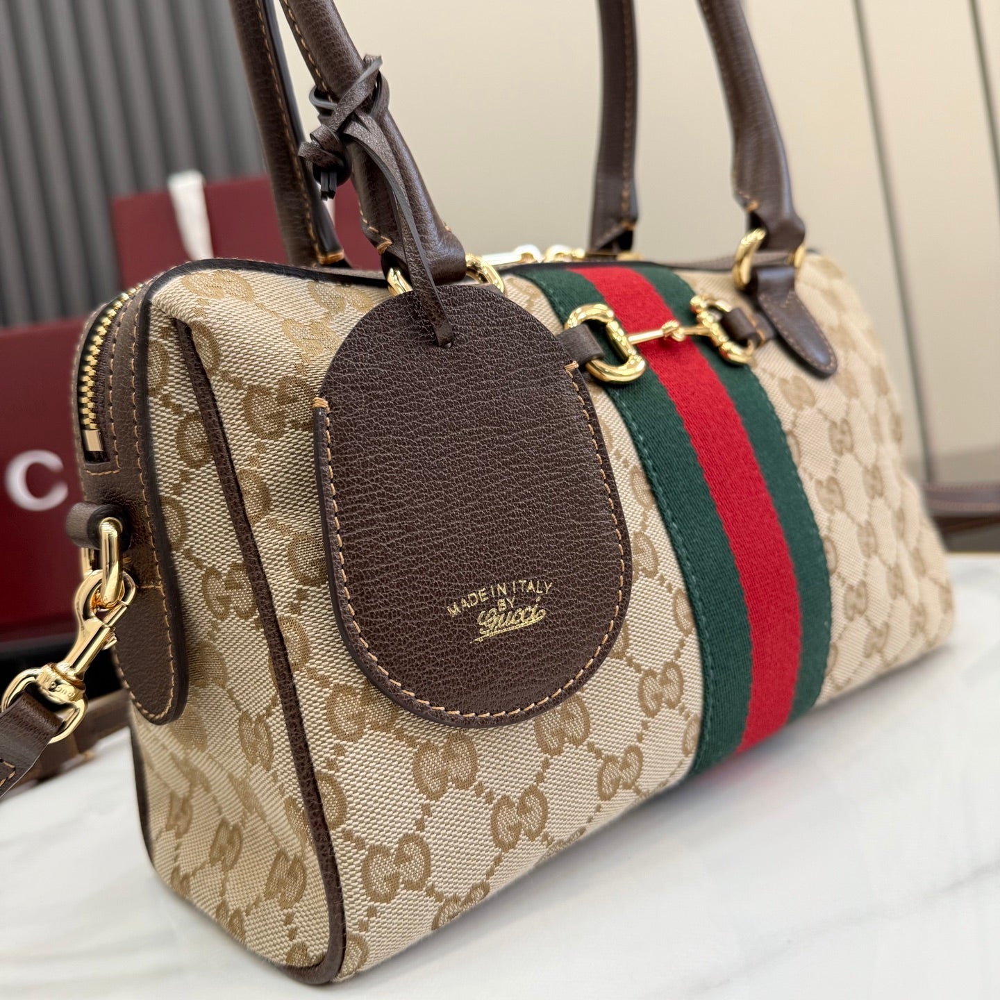Striped GG canvas handbag with brown leather oval patch, zip closure and dual straps