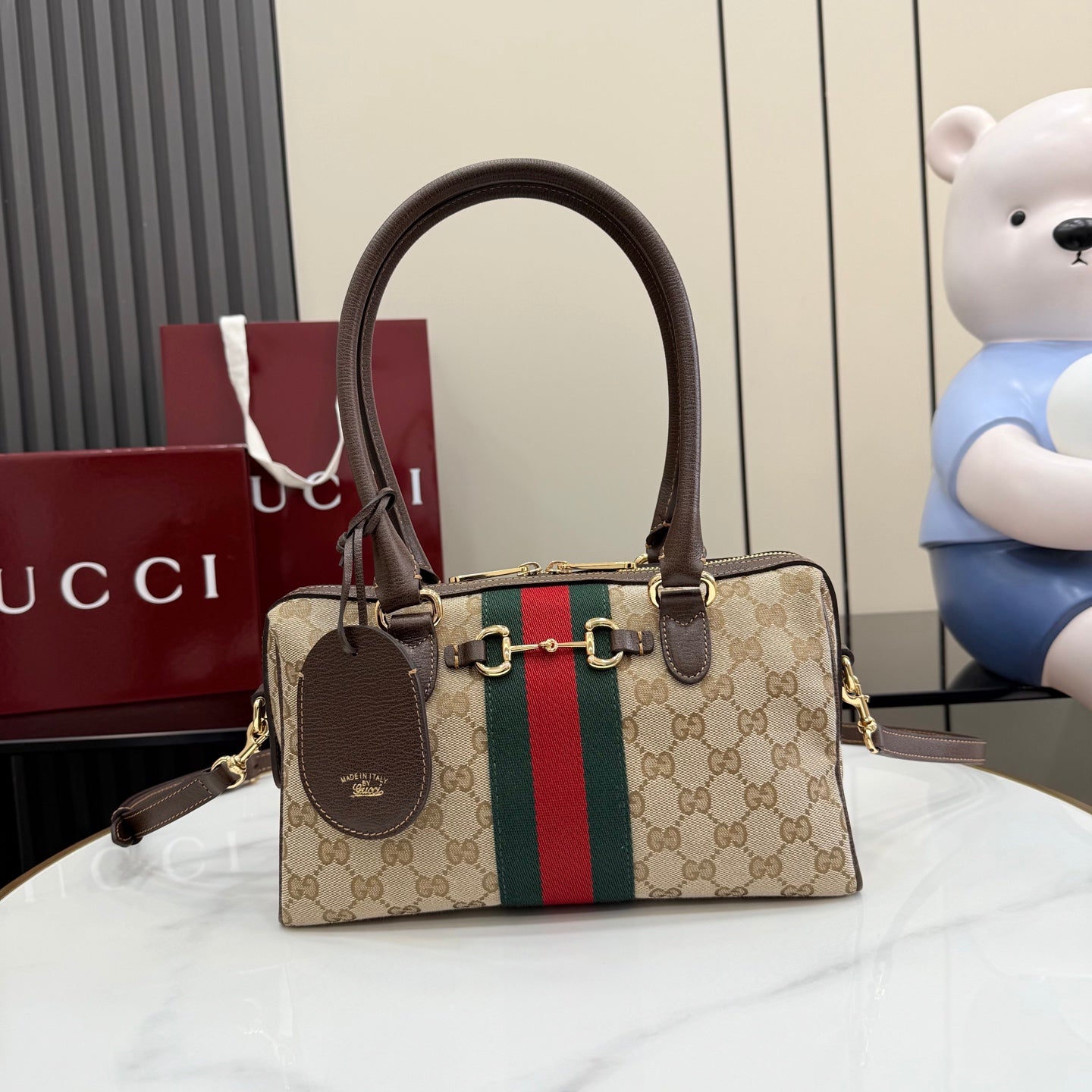 Gucci canvas handbag with brown leather handles, gold hardware, and green-red stripe panel