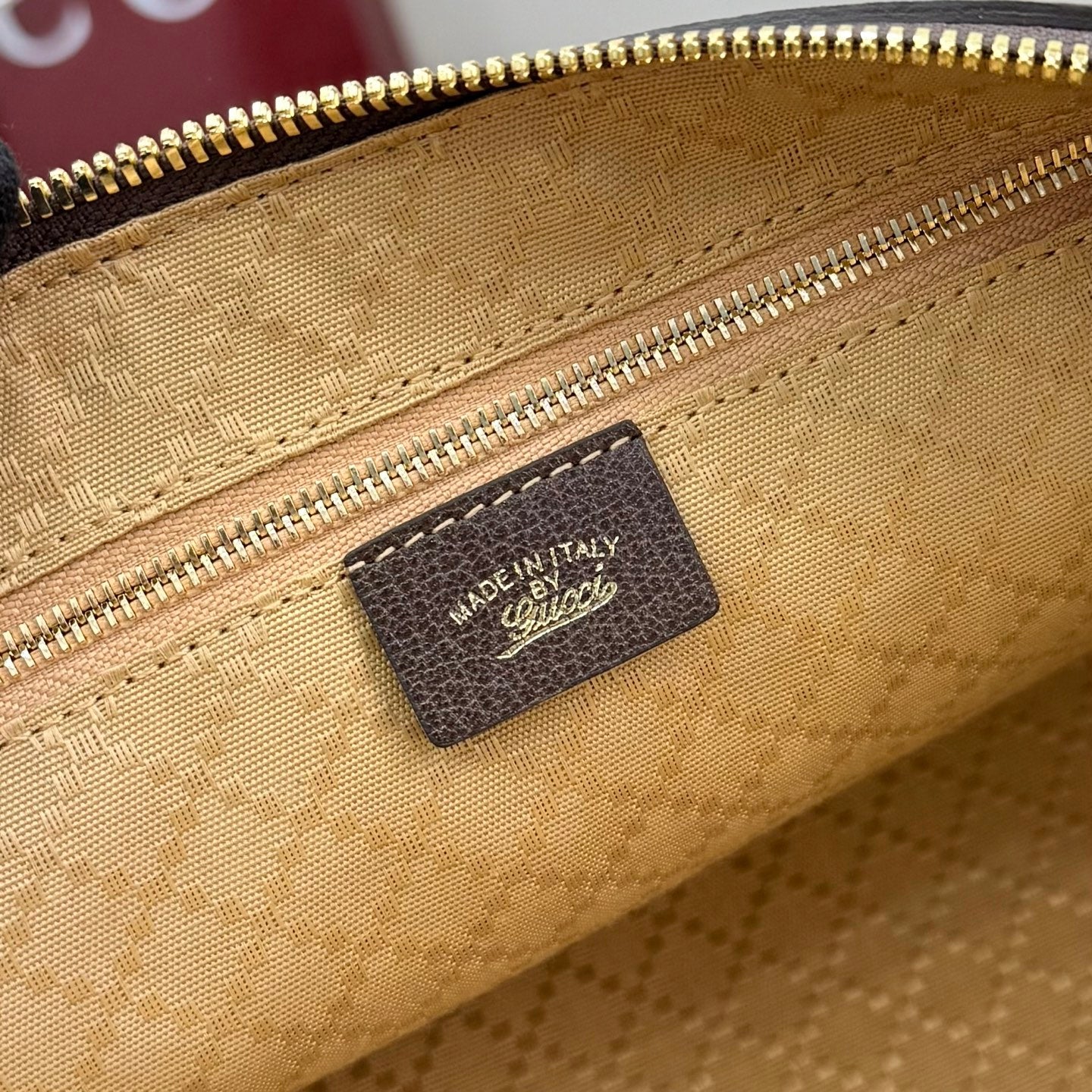 Gucci handbag interior close-up showing brown leather brand patch on tan lining