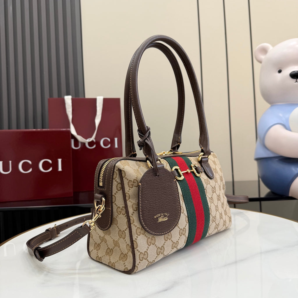 Gucci canvas handbag with brown leather trim, charm tag, and shoulder strap