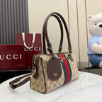 Gucci canvas handbag with brown leather trim, charm tag, and shoulder strap