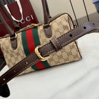 Designer striped canvas handbag with brown leather trim, top handles and gold hardware
