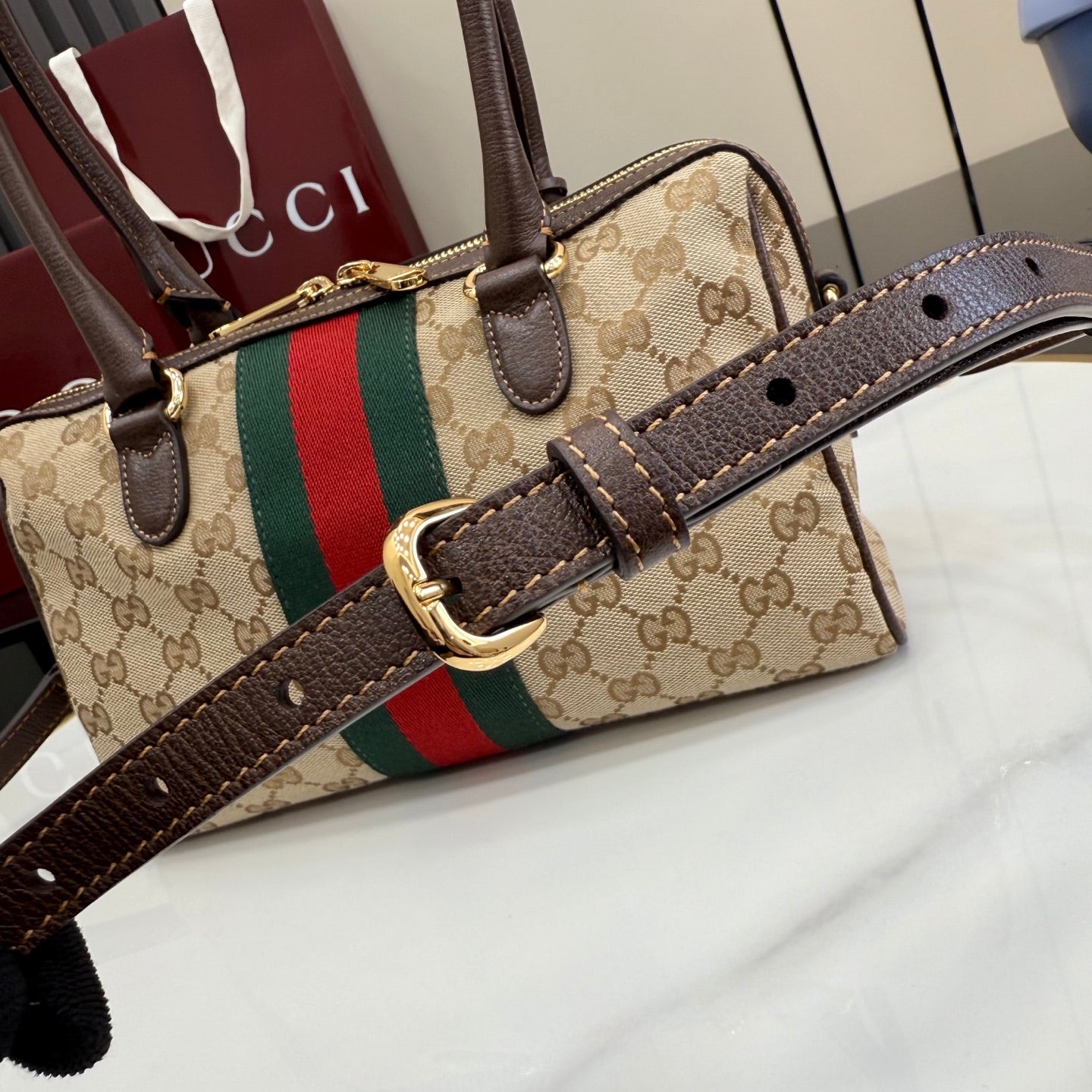 Designer striped canvas handbag with brown leather trim, top handles and gold hardware