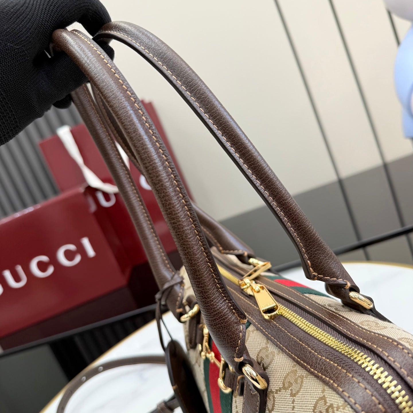 Gucci handbag close-up of brown top handles with gold hardware and zipper edge