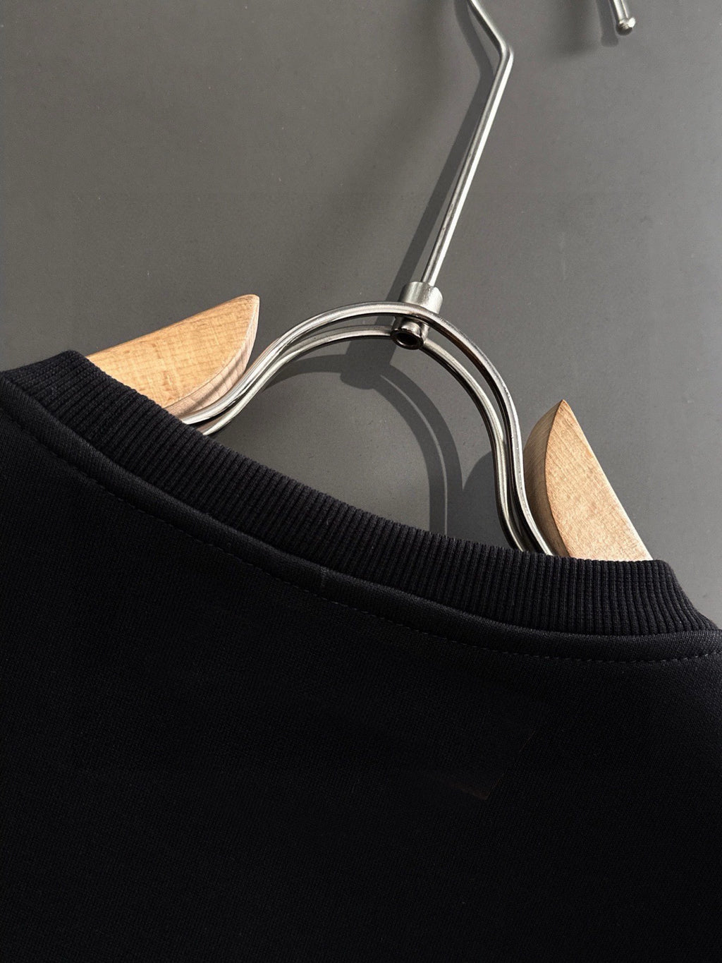 Black sweatshirt ribbed collar detail, on hanger