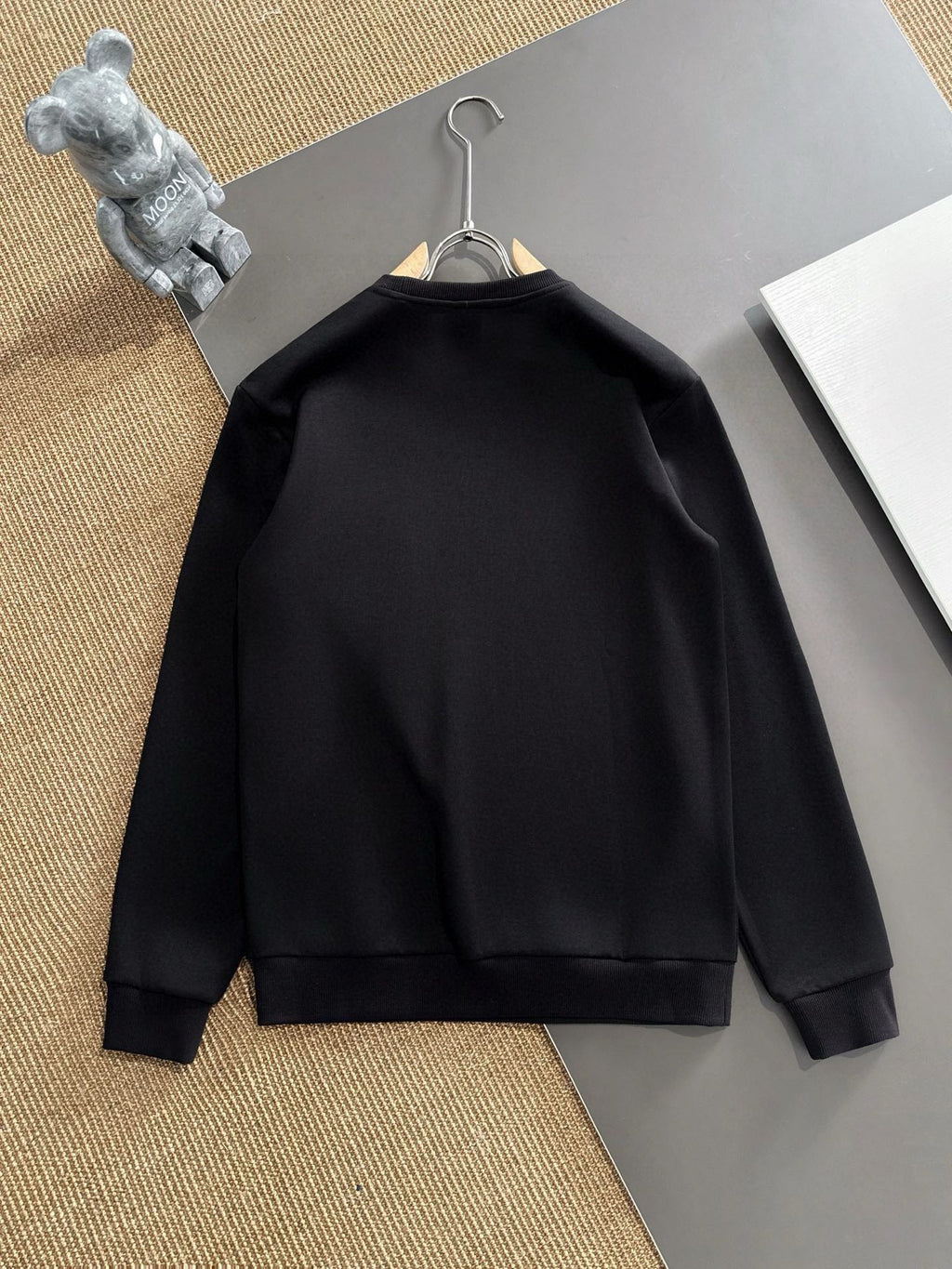 Black crewneck sweatshirt back view, plain with no visible print