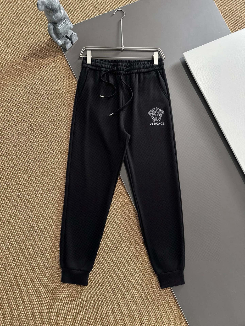 Black jogger pants with drawstring waistband and Versace patch logo