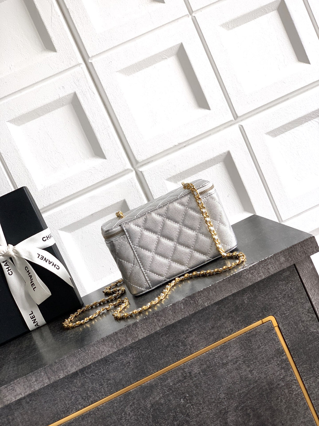 Light gray quilted Chanel bag with gold chain strap across the front flap.