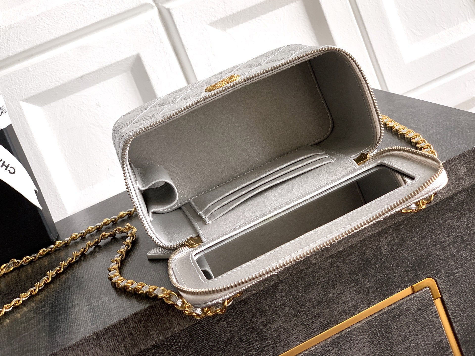 Light gray Chanel bag open top showing structured interior and zip lining.