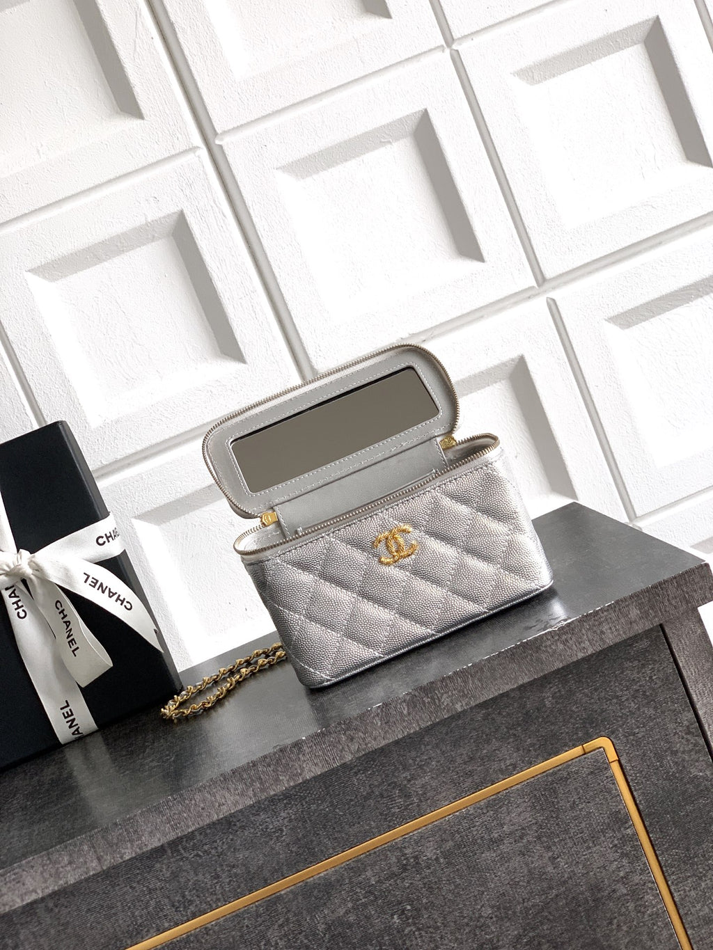 Light gray quilted Chanel bag with gold-tone chain strap and zip top opening.