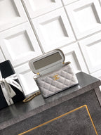 Light gray quilted Chanel bag with gold-tone chain strap and zip top opening.