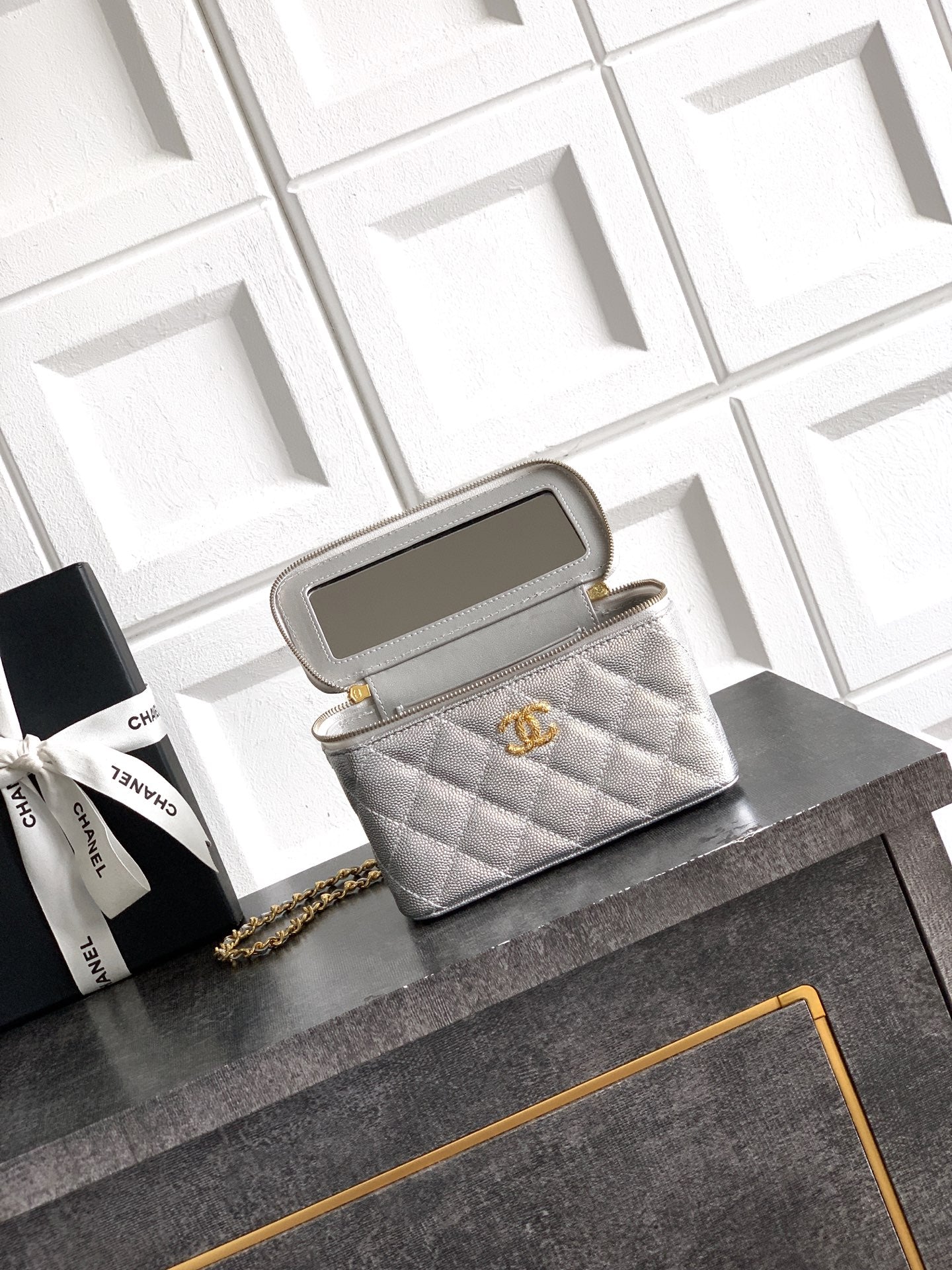 Light gray quilted Chanel bag with gold-tone chain strap and zip top opening.