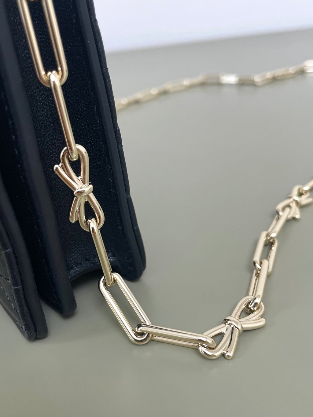 Dior chain strap with gold links attached to a quilted dark navy bag