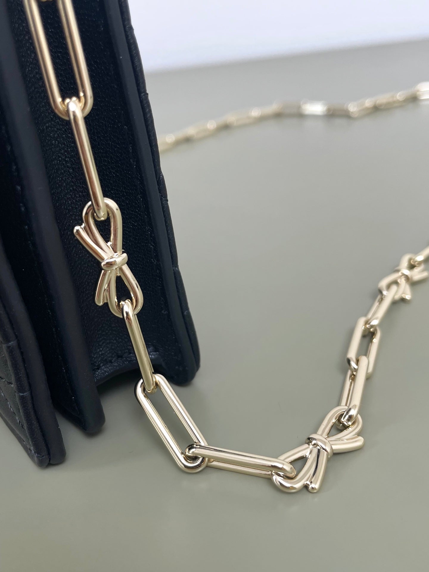 Dior chain strap with gold links attached to a quilted dark navy bag