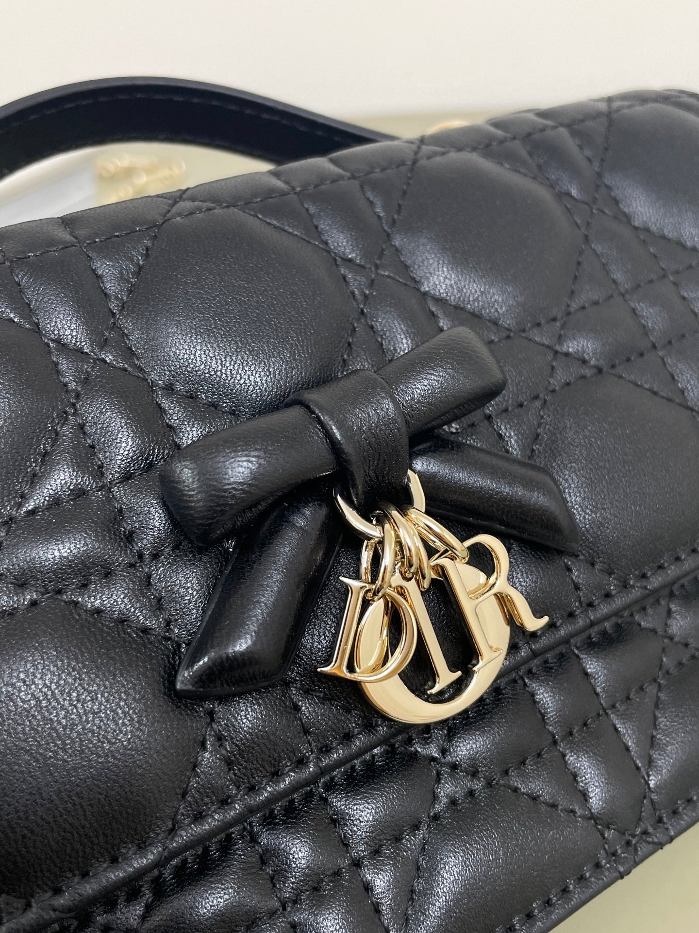 Dior quilted leather bag front with black bow and gold-tone logo clasp, dark navy