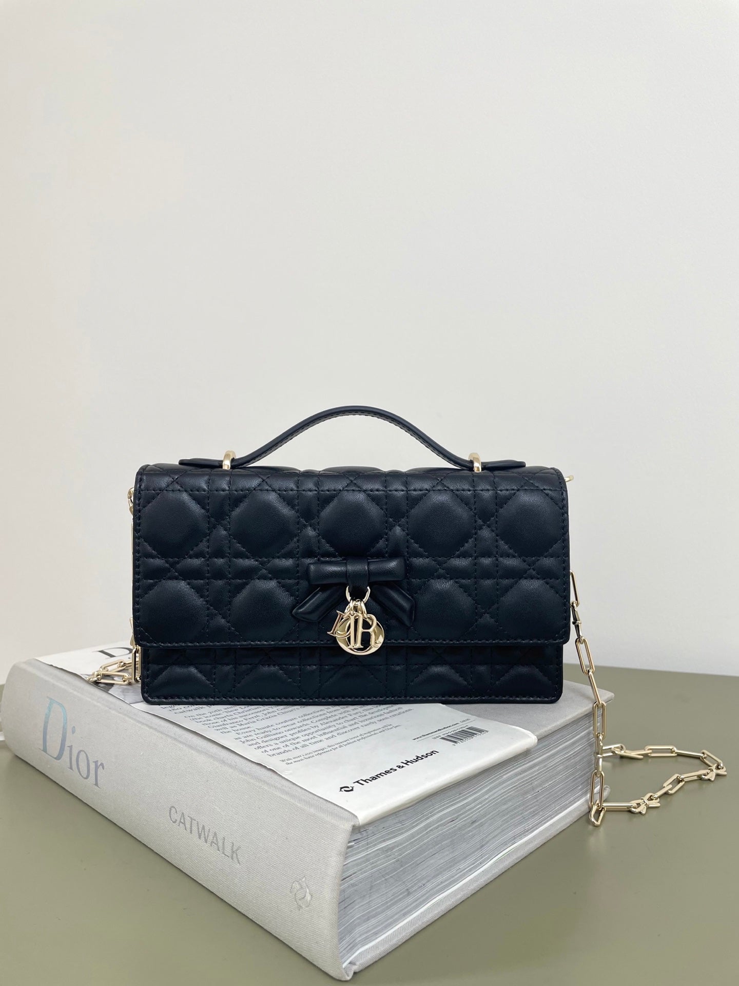Dior quilted leather handbag with top handle, bow front, and flap closure, dark navy