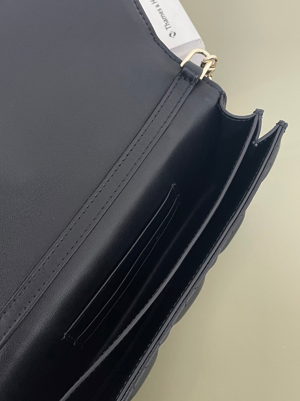 Dior leather bag side with stitched edge and gold-tone clasp hardware, dark navy