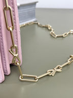 Pink leather shoulder bag with gold chain strap and D-ring links