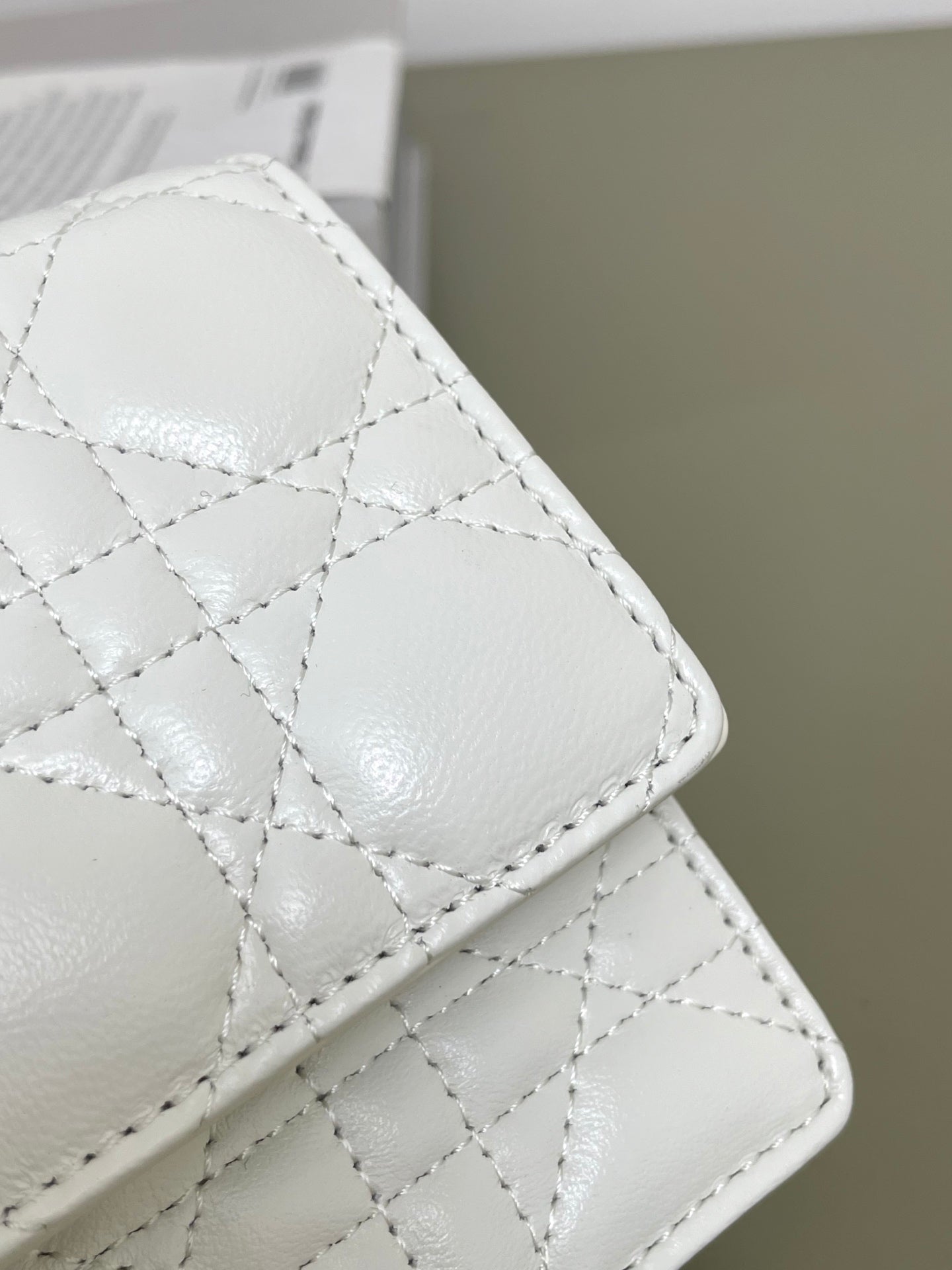 White quilted bag with stitched diamond pattern and rounded corner flap