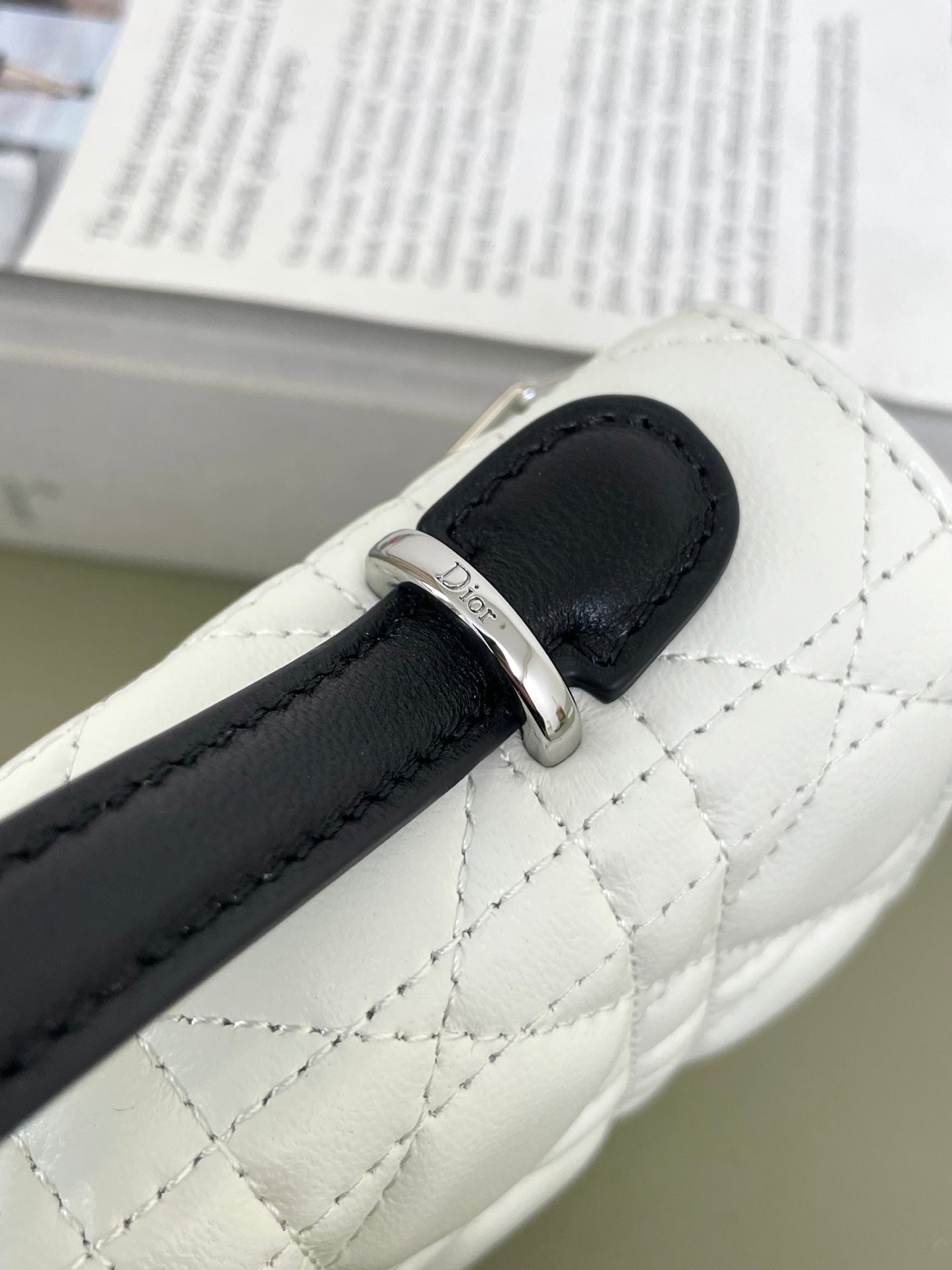 White quilted bag strap detail with black leather tab and silver buckle