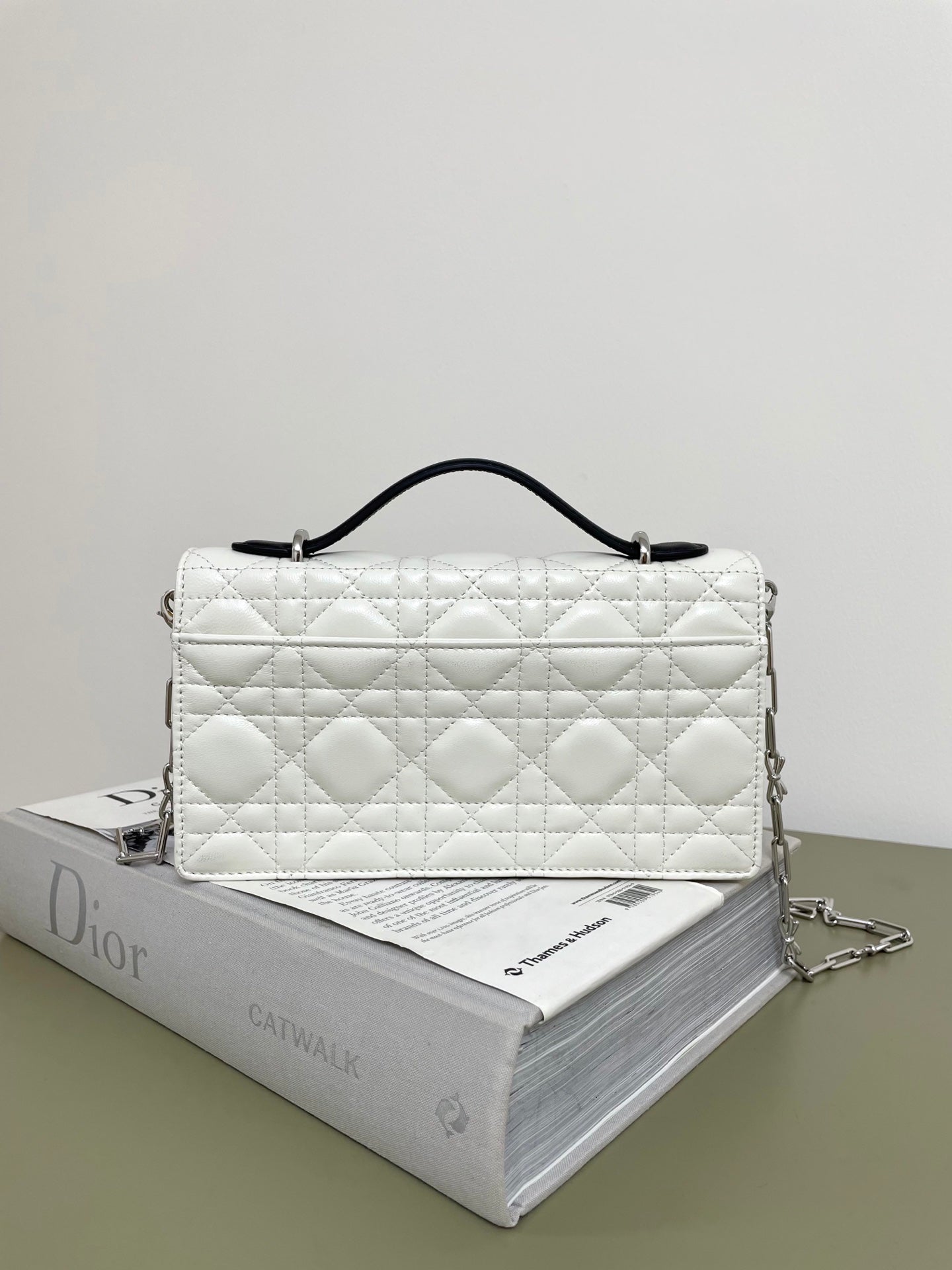 Quilted white shoulder bag with black bow closure and chain strap