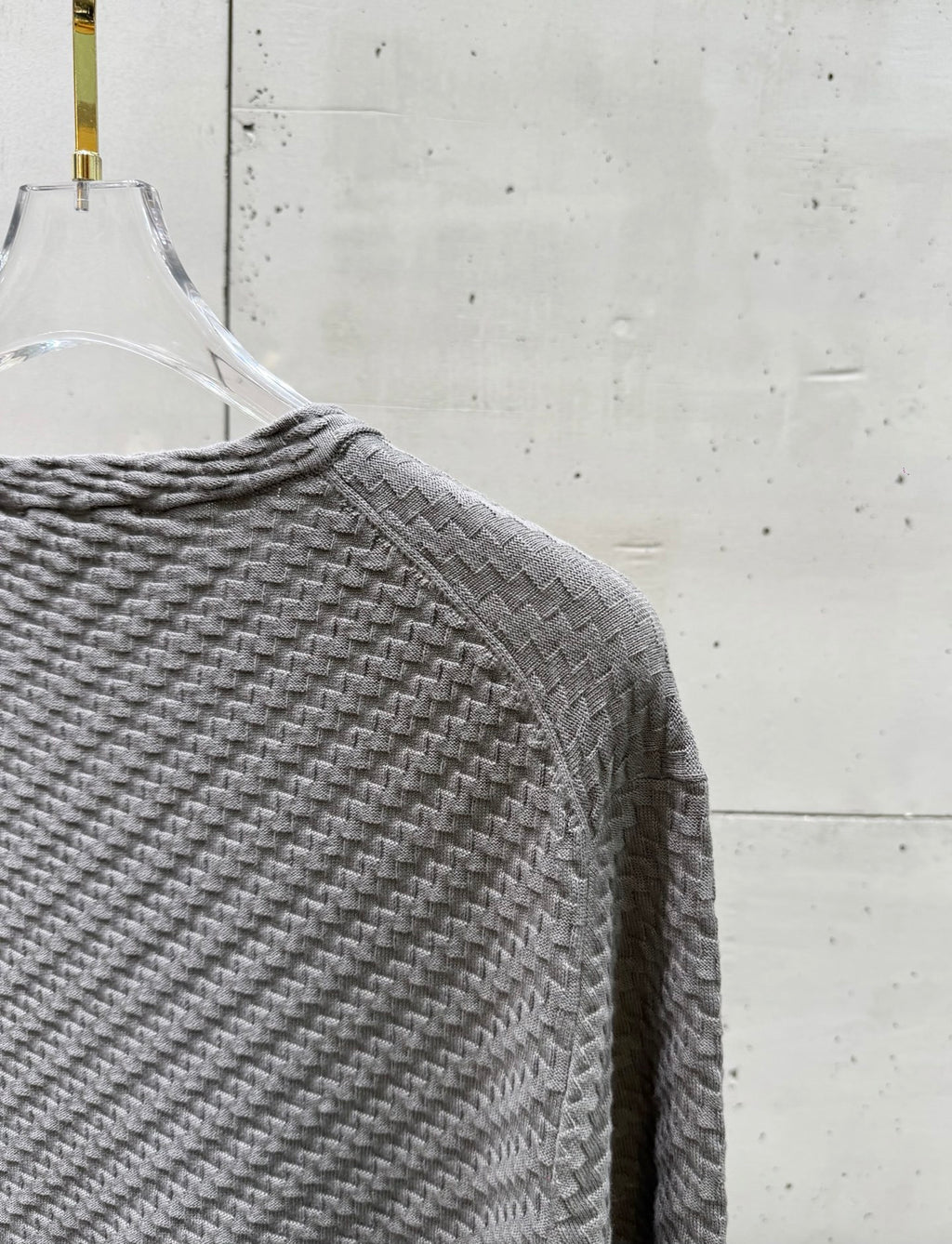 Amiri knit sweater shoulder and sleeve in heather gray, textured knit fabric.