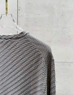 Amiri knit sweater shoulder and sleeve in heather gray, textured knit fabric.