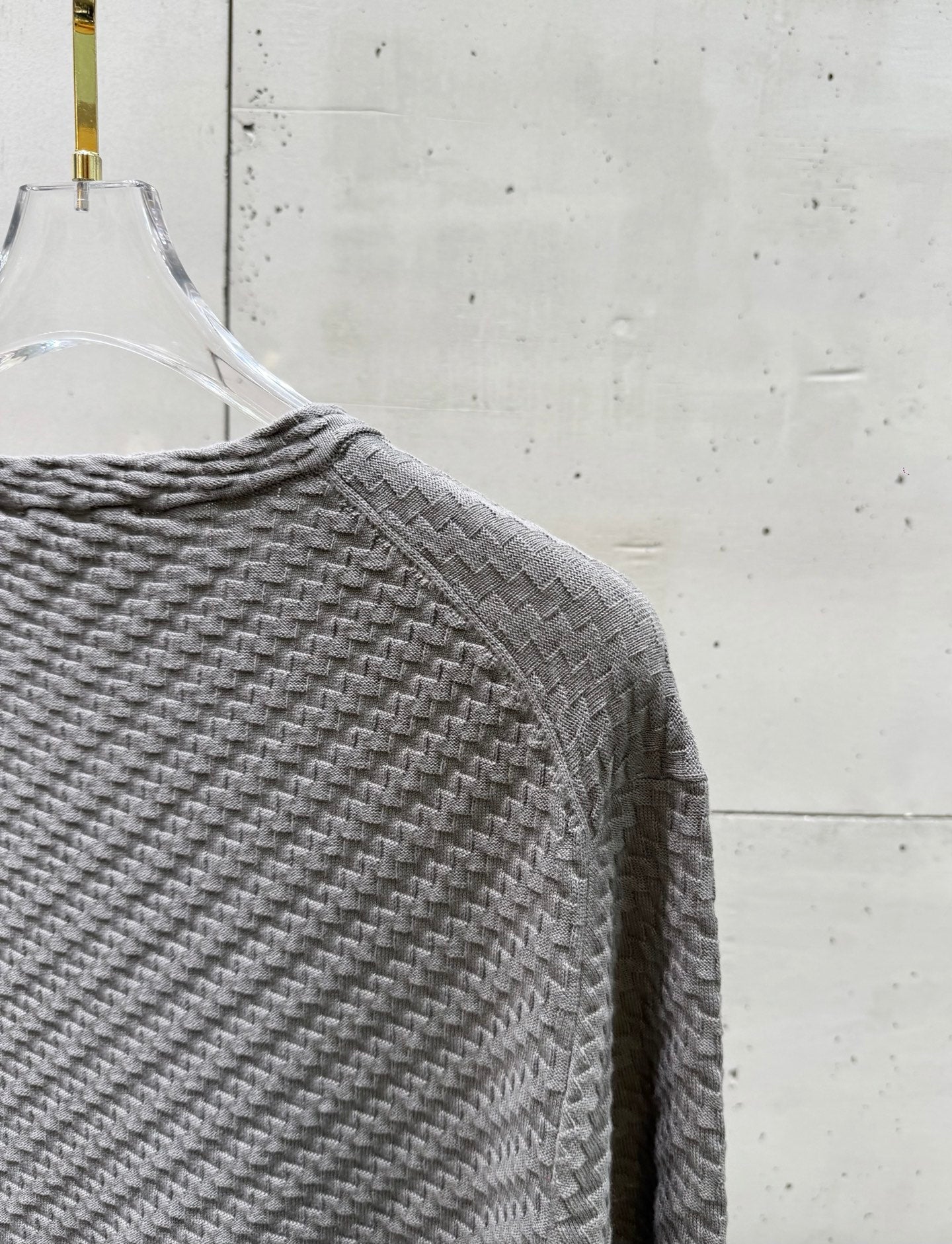 Amiri knit sweater shoulder and sleeve in heather gray, textured knit fabric.