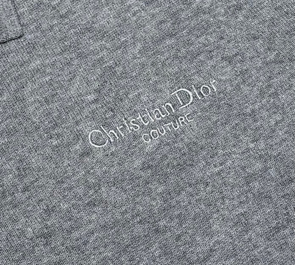 Prada polo shirt logo close-up: “Christian Dior Couture” text on heather gray knit