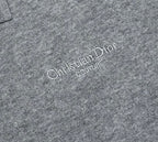 Prada polo shirt logo close-up: “Christian Dior Couture” text on heather gray knit