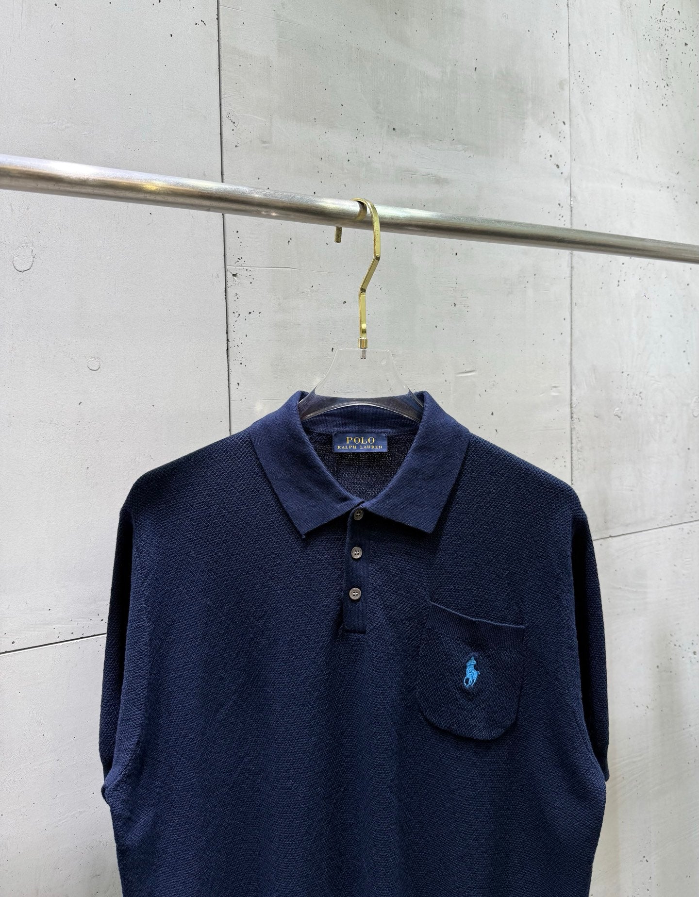 Navy polo sweater front with embroidered logo and buttoned chest pocket