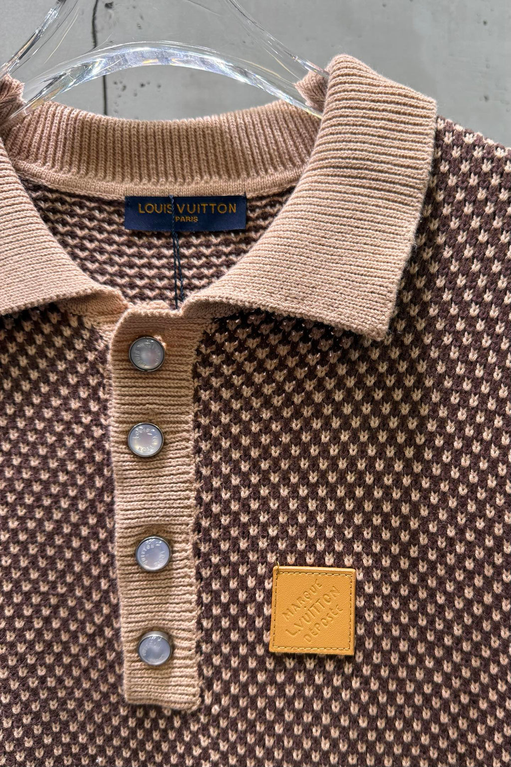 Knit polo shirt neckline detail with ribbed collar, button placket, chest logo patch