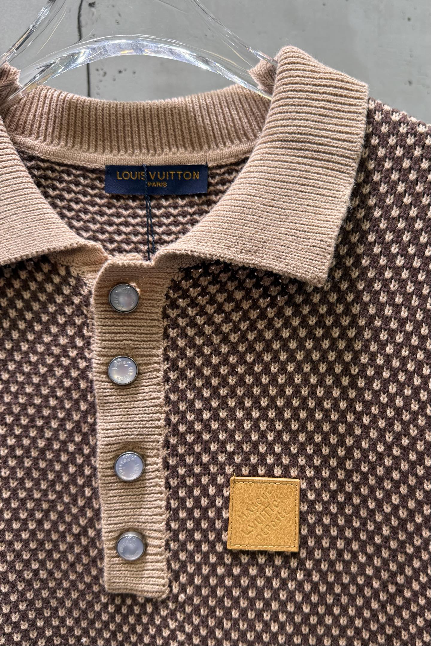 Knit polo shirt neckline detail with ribbed collar, button placket, chest logo patch