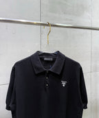 Black polo shirt with dark collar, button placket, and small chest logo