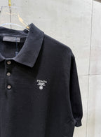 Black polo shirt close-up with collar, button placket, and PRADA chest logo